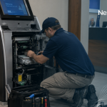 Field technician servicing an open Hyosung ATM inside a bank branch lobby